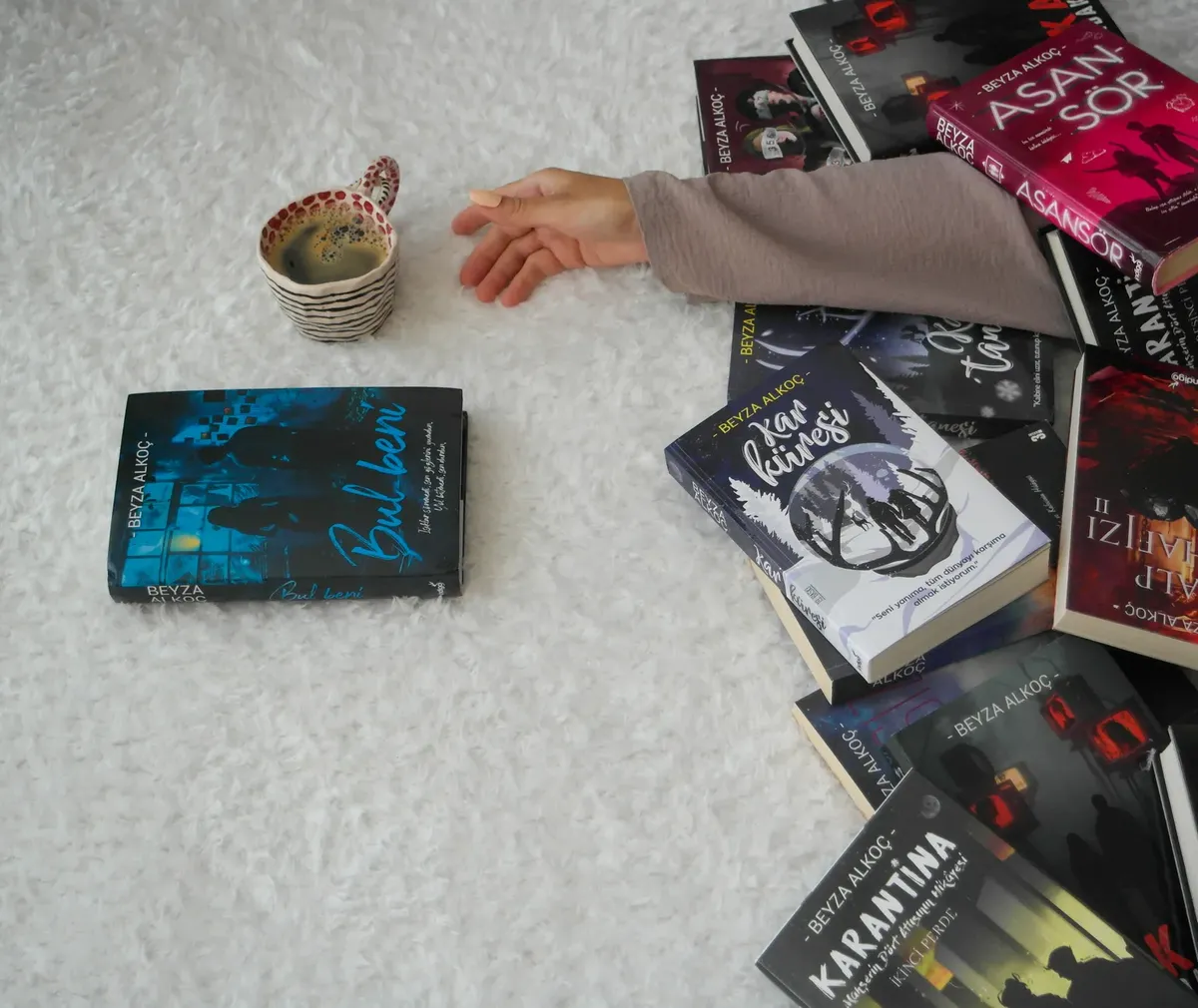 A warm setting featuring an arm amidst books and a cup of tea, ideal for book lovers.