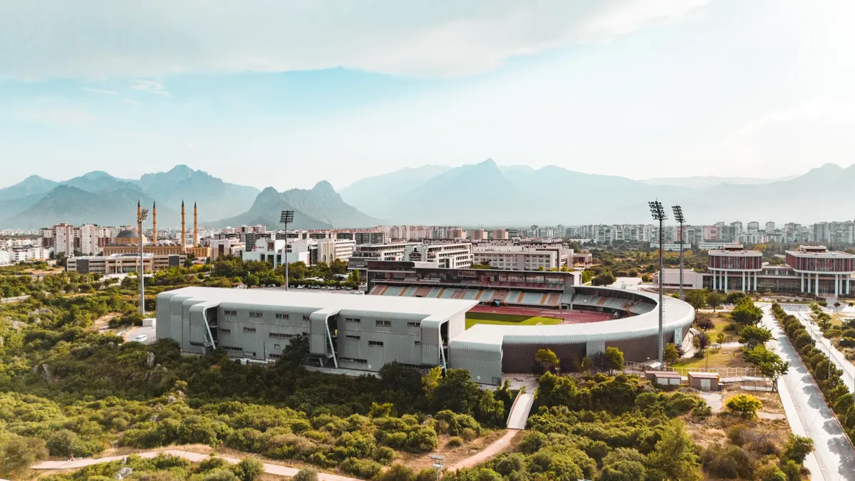 Stunning aerial view of a stadium in Antalya, surrounded by mountains and cityscape.