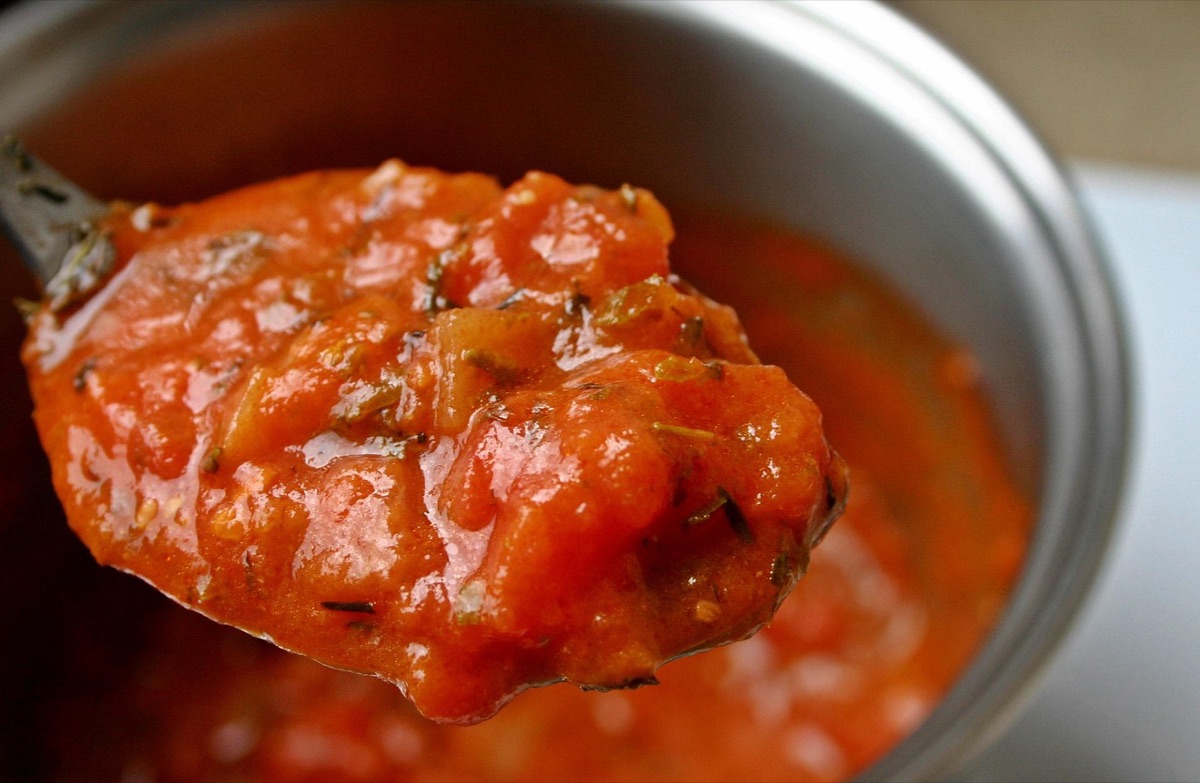 Turkse chef met een pot tomatensaus, keuken, keukenstof