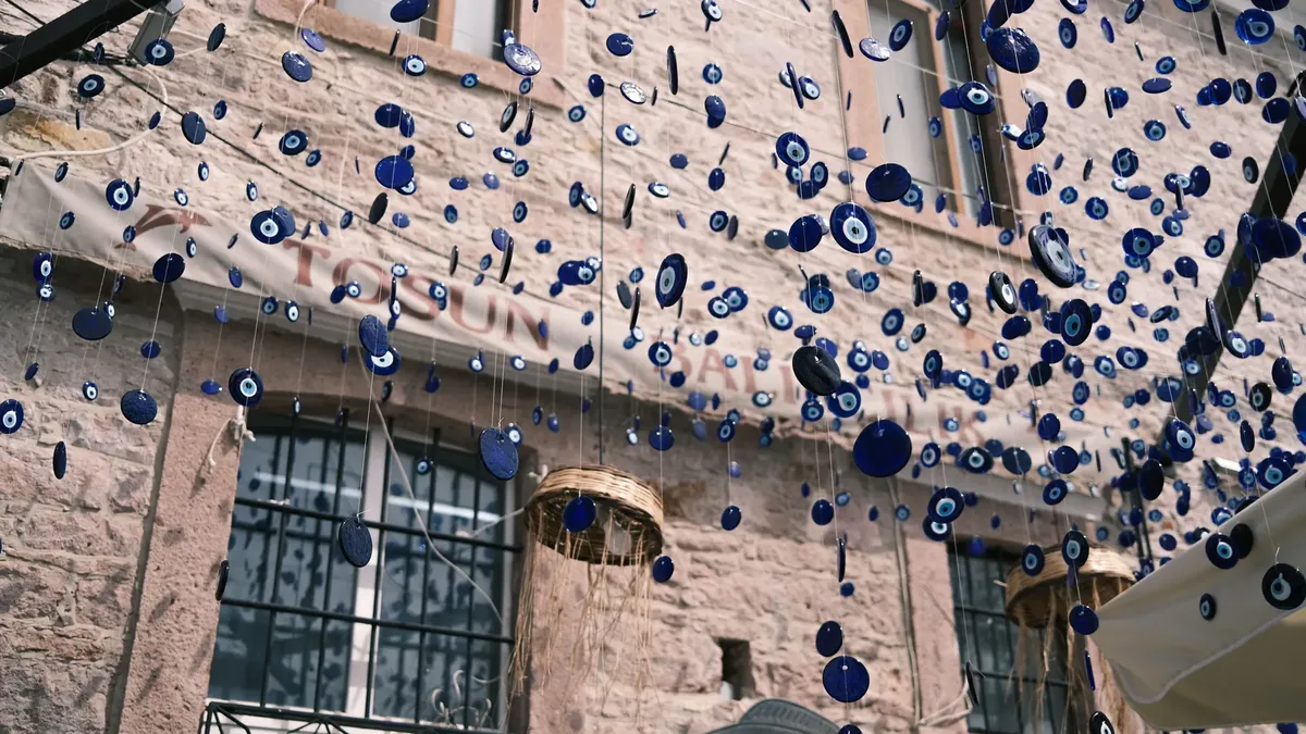 Blue Turkish Nazar pendants hang decoratively in a vibrant urban setting.