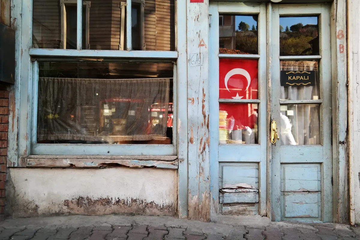 A weathered wooden facade in İstanbul, featuring a Turkish flag and closed sign.