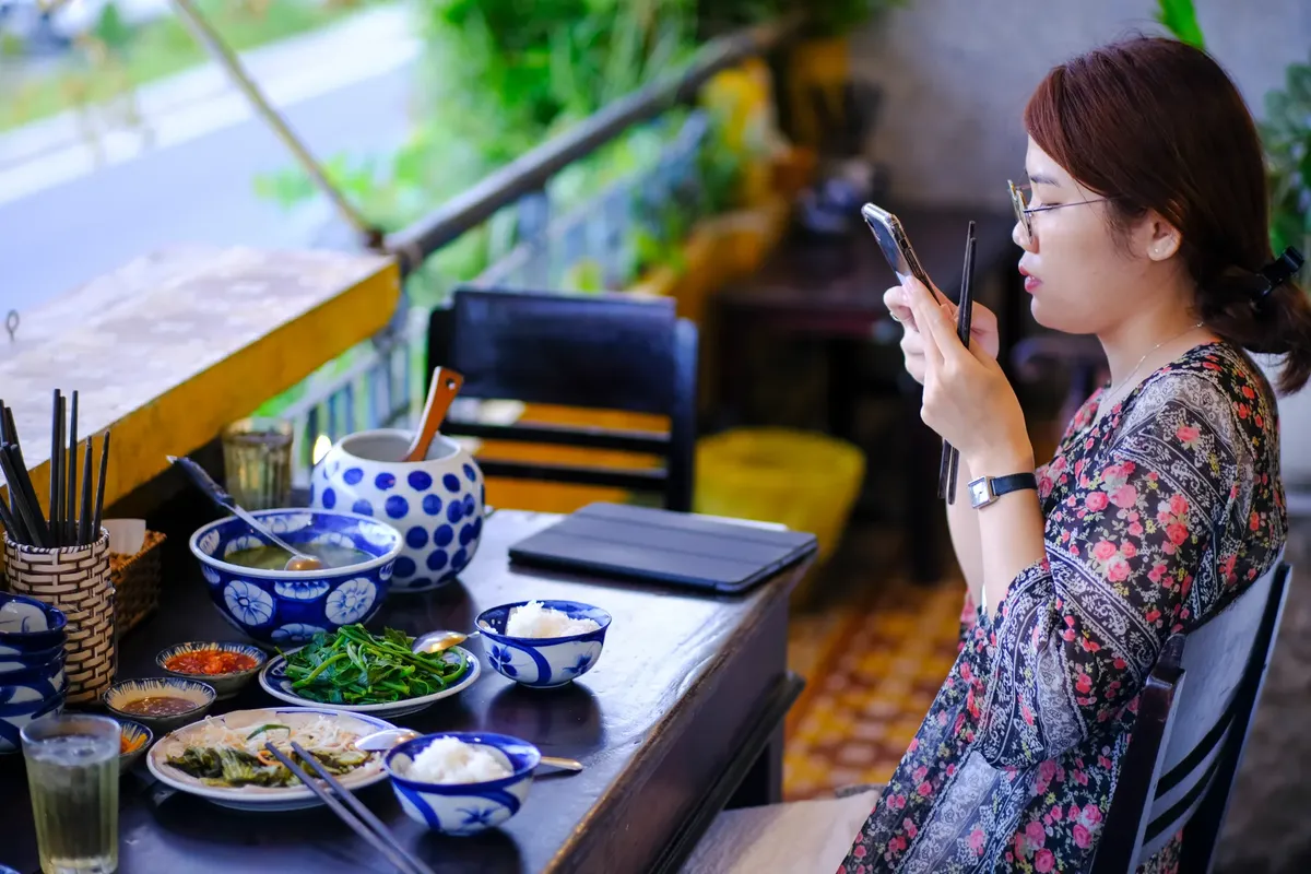A woman photographs her food at an outdoor café in Da Nang, Vietnam.
