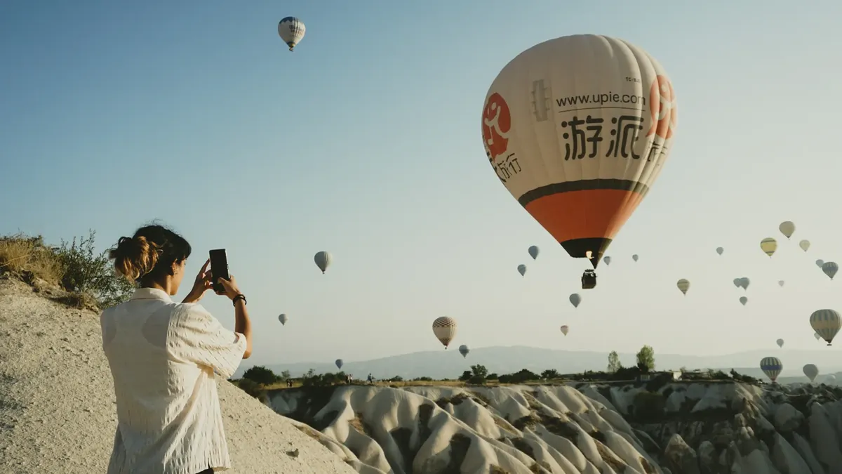 Woman photographing hot air balloons in Cappadocia, Turkey. Scenic view and adventure travel.