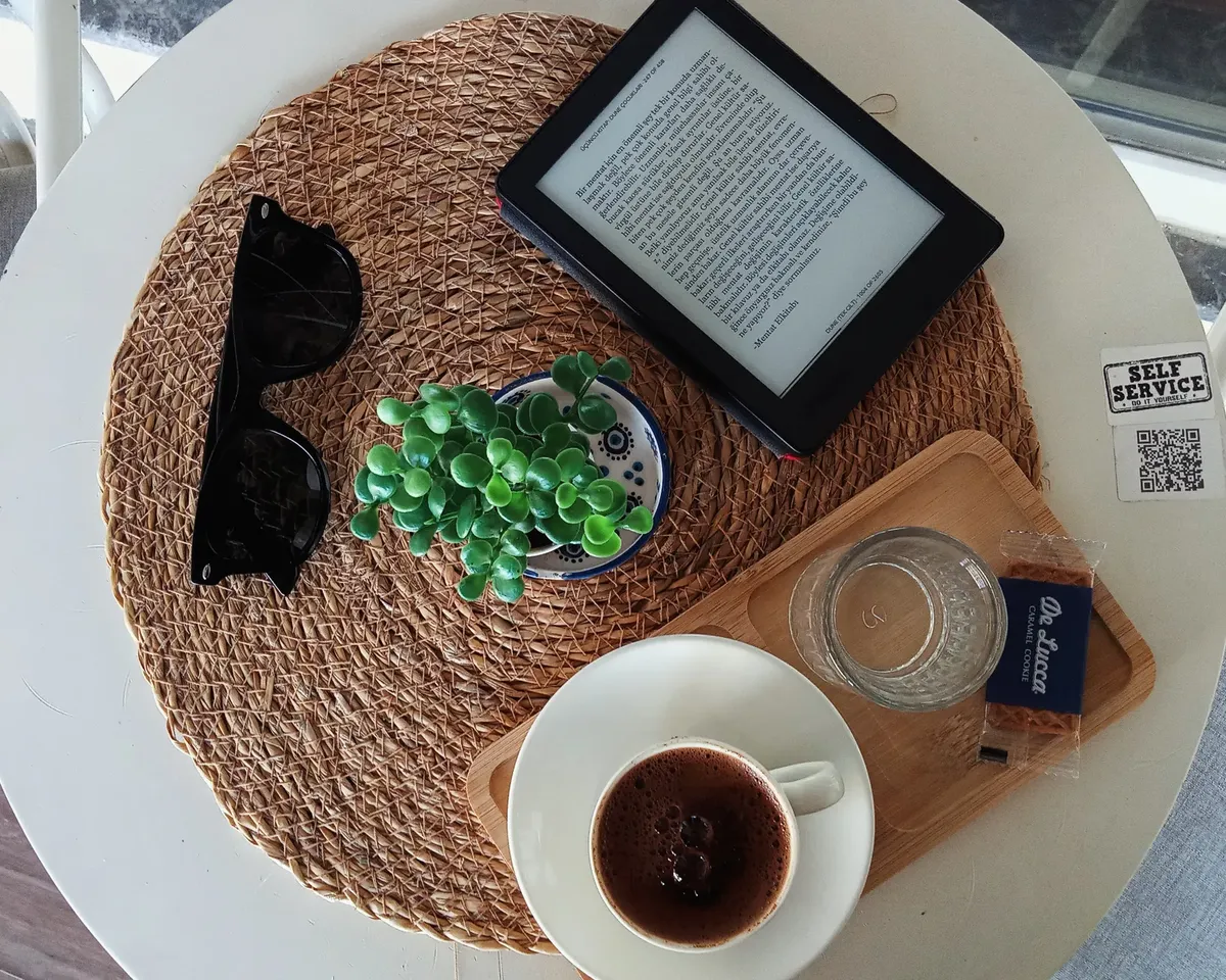 Top view of a cozy café table with an ebook, Turkish coffee, and succulent plant.
