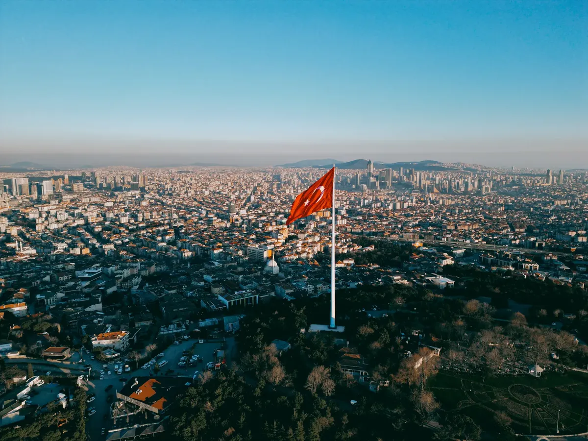 Stunning aerial shot of the Turkish flag flying over the expansive skyline of Istanbul at daytime.